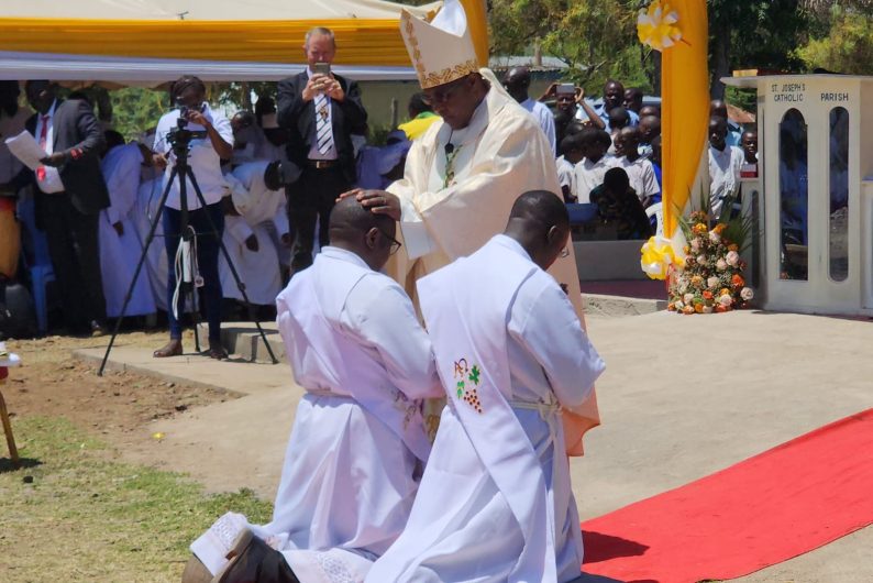 Fathers Joseph Maundu and Cavine Okello kneel before their bishop as they are ordained as priests.